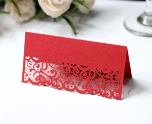 Detail of red laser-cut place card with intricate lace and heart patterns for weddings