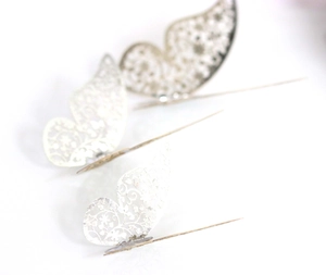 Detail view of three silver hollow butterfly decorations with a metallic reflective finish