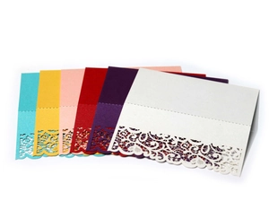 Close-up of laser cut lace patterns on colorful cardstock wedding table place cards