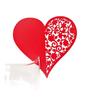 Laser-cut red heart-shaped wedding place card with intricate floral hollow design on glass