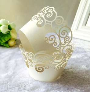 Detail view of laser-cut white pearlescent cupcake wrappers with scrollwork lace pattern