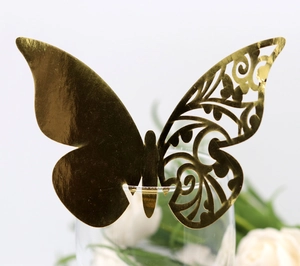 Detailed view of a golden 3D butterfly place card with laser-cut hollow pattern on glass