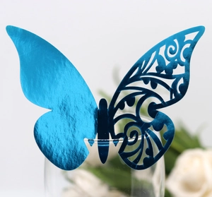 Close-up of blue metallic laser-cut butterfly card on glass for wedding table decor