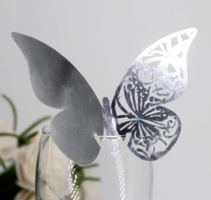 Detailed view of a silver mirror butterfly name card on a glass for wedding decor