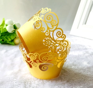 Detailed laser-cut gold cupcake wrapper with elegant swirl pattern and pearlescent finish