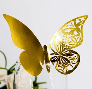 Elegant gold butterfly place card with laser-cut hollow design on a wine glass rim