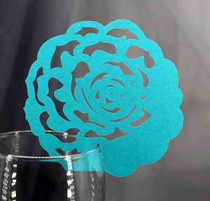 Close-up of laser-cut teal rose place card for glasses in a wedding or party setting