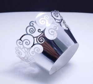 Detail of silver laser-cut cupcake wrappers with elegant hollowed cloud patterns