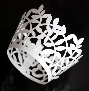 Macro detail of white laser-cut cupcake wrapper with pearlized leaf and vine pattern