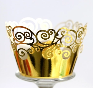 Macro view of golden laser-cut cupcake wrapper with elegant spiral filigree patterns