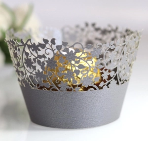 Detail of laser-cut silver cupcake wrappers featuring intricate floral vine patterns