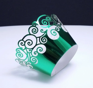 Detail of laser-cut green metallic cupcake wrappers with intricate scrollwork hollow design