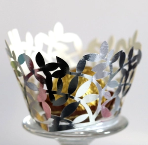 Macro view of silver laser-cut cupcake wrapper with elegant leaf patterns and chocolate