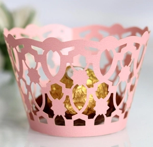 Pink laser-cut lace cupcake wrappers with intricate floral patterns for bakery decor