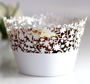 Macro shot of white laser-cut cupcake wrappers with floral patterns and pearl finish