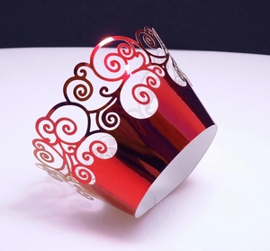Close-up of laser-cut red metallic cupcake wrapper with elegant filigree pattern