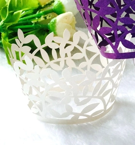 Macro view showing white and purple laser-cut cupcake wrappers with vine leaf patterns