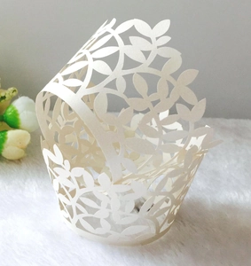 Detail of laser-cut cream cupcake wrapper with intricate leaf vine patterns for events