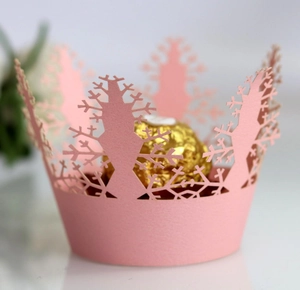 Detail showing pink laser-cut cupcake wrapper with snowflake patterns and gold candy inside