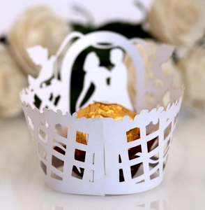Detailed laser cut white cupcake wrapper featuring a romantic wedding silhouette design