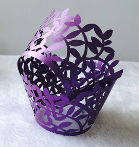 Detailed laser-cut purple cupcake wrapper with elegant leaf pattern on white fur texture