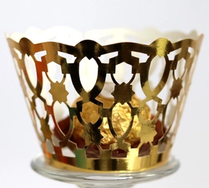 Laser-cut gold cupcake wrapper with intricate geometric star patterns for party decor