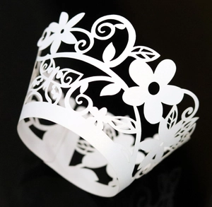 Detailed laser-cut floral pattern on a white cupcake wrapper for elegant dessert styling