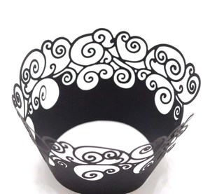 Macro detail of laser-cut cupcake wrapper featuring intricate black swirl vine patterns