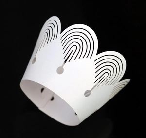 Macro shot of white laser-cut cupcake wrappers with elegant crown pattern for party decor