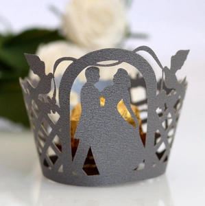 Close-up of laser-cut wedding cupcake wrappers with romantic bride and groom silhouette
