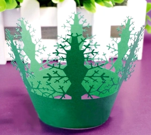 Macro detail of laser-cut Christmas tree cupcake wrappers in deep green paper