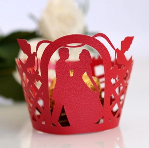 Detail of red laser-cut cupcake wrapper featuring bride and groom silhouette and birds
