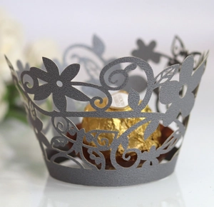 Macro shot of silver laser-cut floral cupcake wrappers and luxury chocolate display