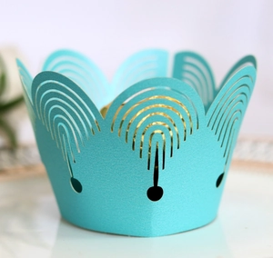 Macro shot of laser-cut mint blue cupcake wrappers featuring elegant hollow arch designs
