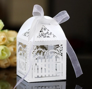 Elegant laser-cut white wedding favor box with ornate fence patterns and white ribbon bow