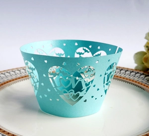 Detail of light blue laser-cut cupcake wrapper with love hearts and lettering for weddings