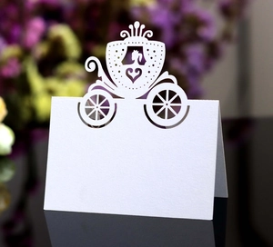 Detail of laser-cut white pumpkin carriage place card on an elegant wedding reception table