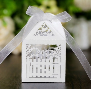 Detailed laser-cut pattern of a white house-shaped wedding favor box with ribbon bow