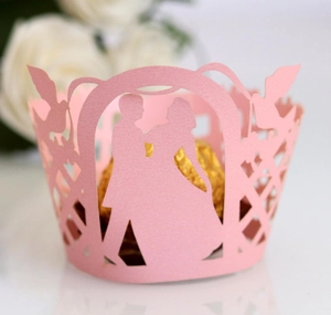 Macro detail of laser-cut pink wedding cupcake wrapper with elegant couple silhouette