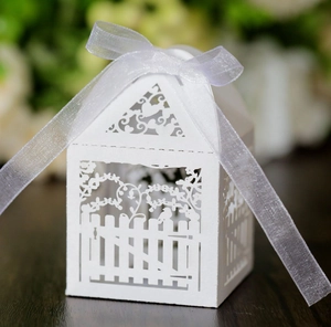 Laser-cut white wedding favor box in house shape with garden fence pattern and ribbon