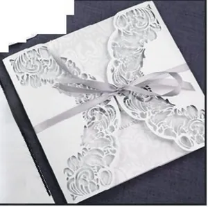 Close-up of laser cut hollow invitation card with elegant silver satin ribbon bow