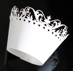 Macro view of white laser-cut floral and heart pattern cupcake wrapper in premium art paper