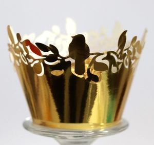 Macro detail of laser-cut gold bird and leaf pattern on cupcake paper wrappers