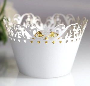 Macro shot of white laser-cut cupcake wrapper with heart patterns and intricate filigree