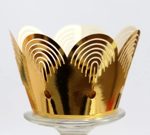 Close-up of golden crown laser-cut cupcake wrappers with shiny metallic finish texture