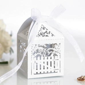 Detail of white laser cut wedding favor box with fence patterns and organza ribbon bow
