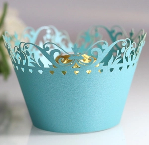 Detail of light blue laser-cut cupcake wrappers with elegant hollow floral heart patterns
