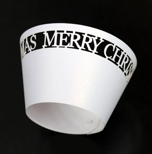 Detailed macro view of white pearlescent cupcake wrapper with Merry Christmas cutout text