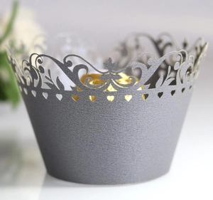 Macro view of laser-cut silver cupcake wrapper with ornate vine patterns and heart details