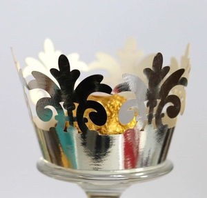 Detail of silver crown laser-cut cupcake wrapper with hollow pattern for weddings